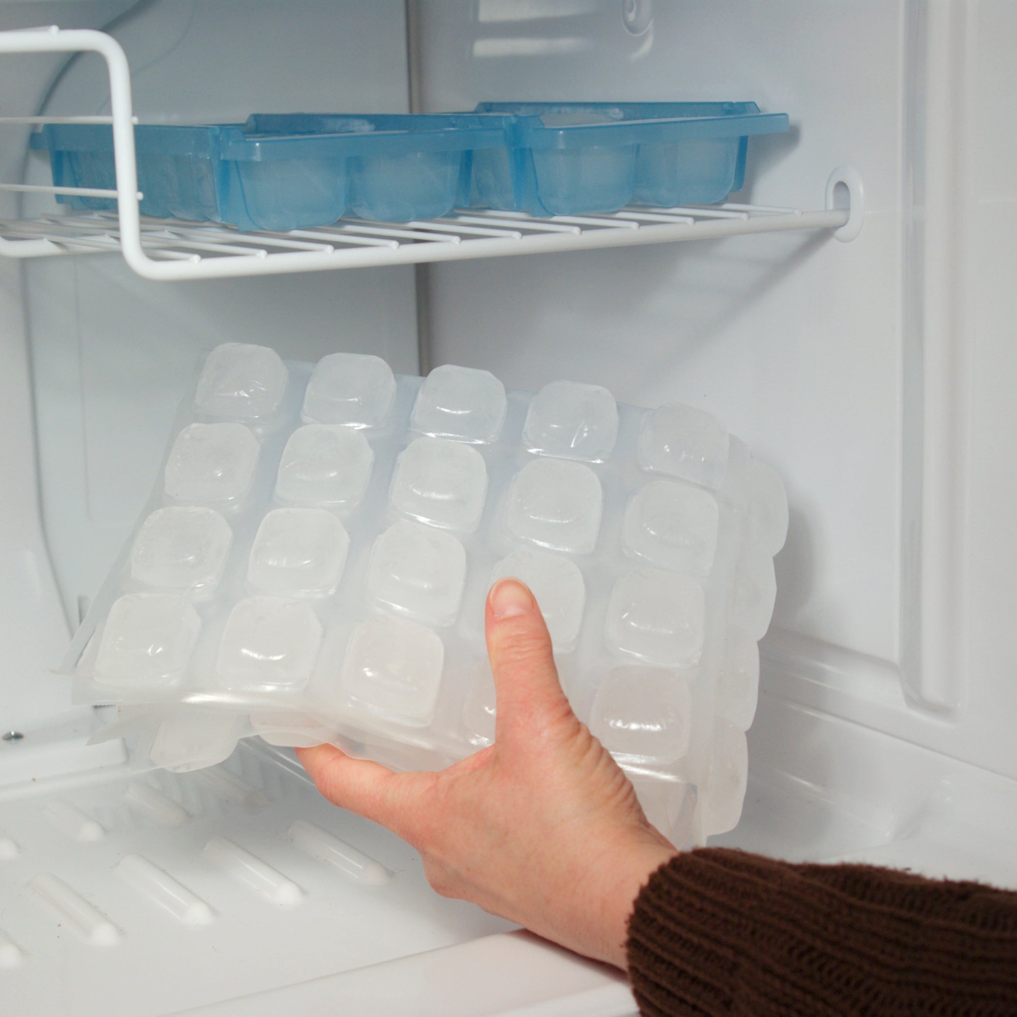 Hand placing folded FlexiFreeze ice sheet into freezer