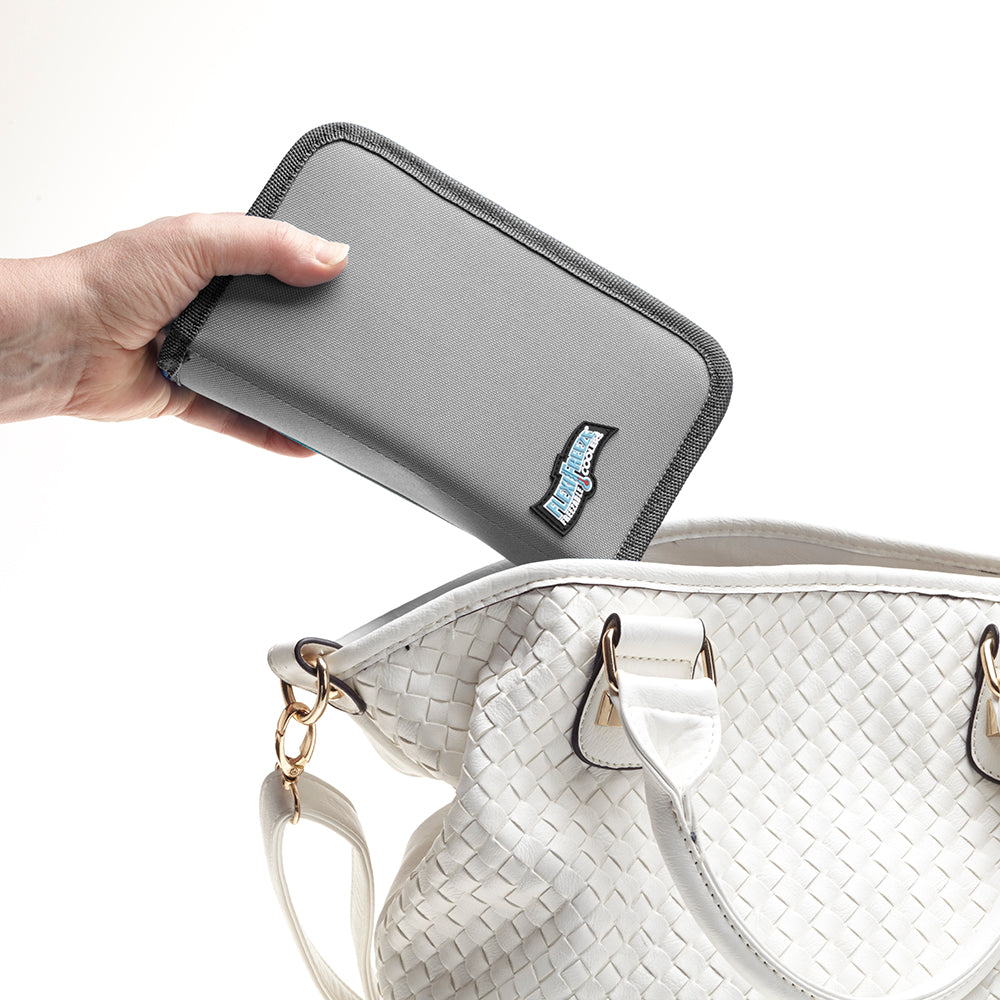 Hand placing Flexifreeze refreezable breastmilk pocketbook cooler, gray, into handbag